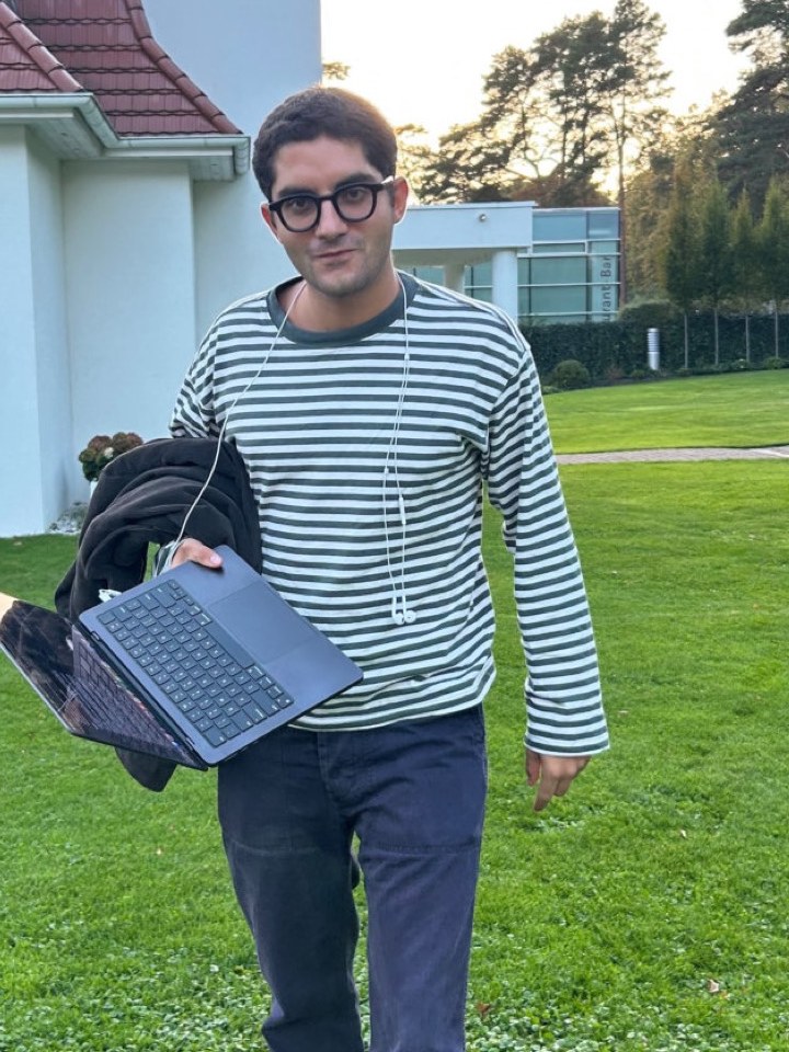 Jacopo walking across a lawn with an open laptop