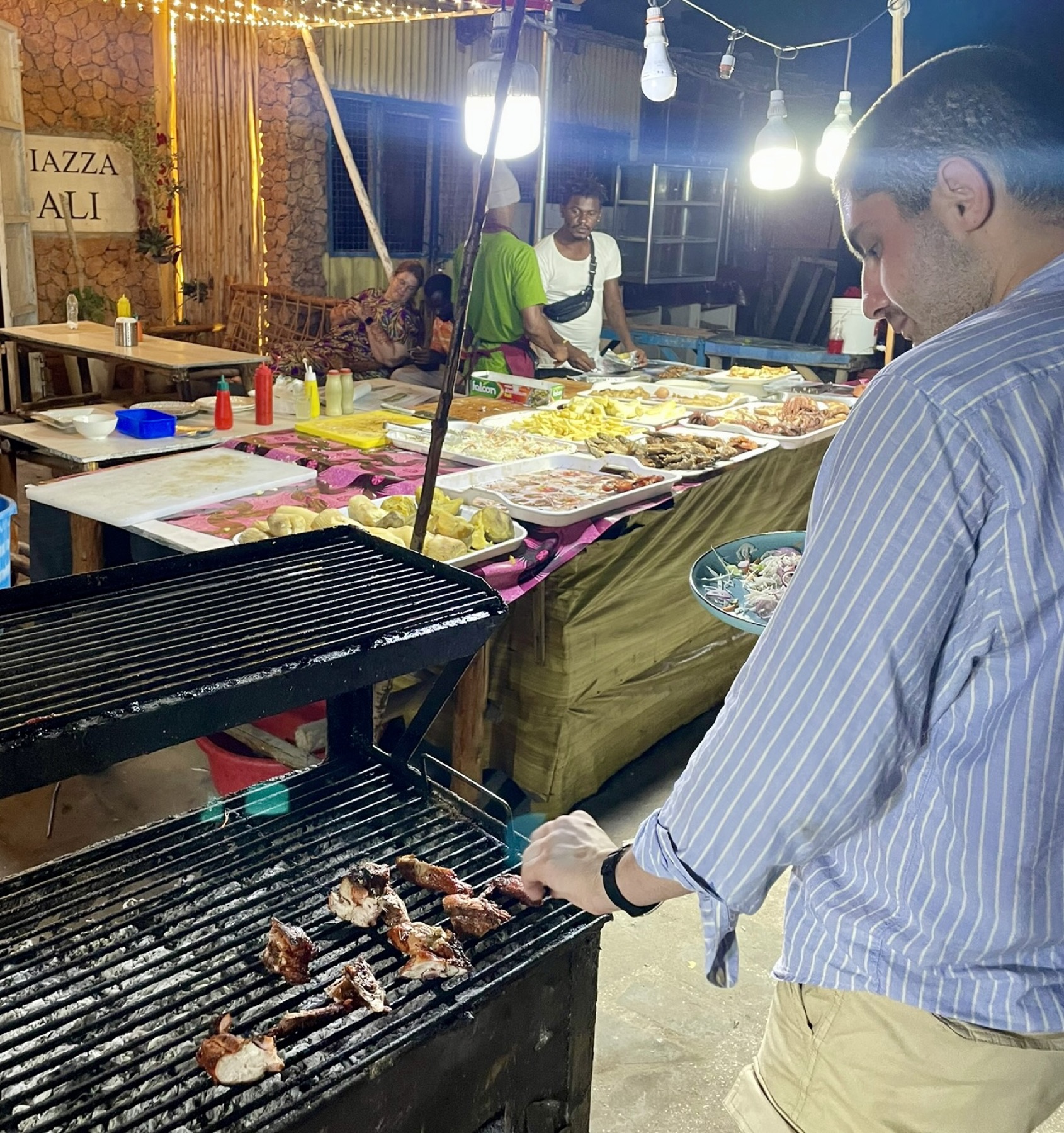 Jacopo turning meat on a street grill at night