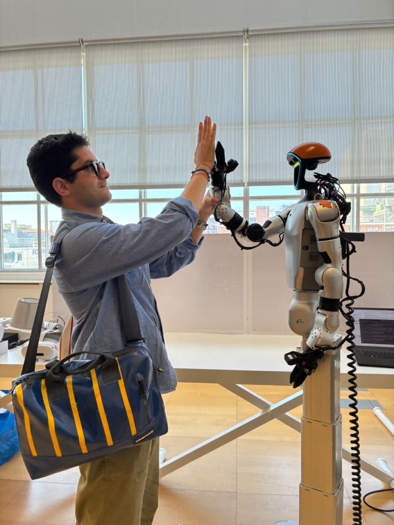 Jacopo high-fiving a humanoid robot in a lab